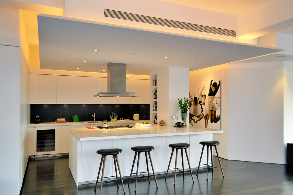 Cette photo montre une cuisine parallèle tendance avec un placard à porte plane, des portes de placard blanches et une crédence noire.