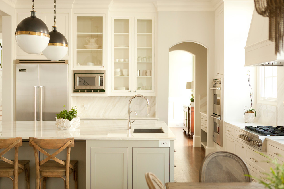 Klassische Wohnküche mit Glasfronten, Küchengeräten aus Edelstahl, weißen Schränken, Küchenrückwand in Weiß und Rückwand aus Stein in Dallas