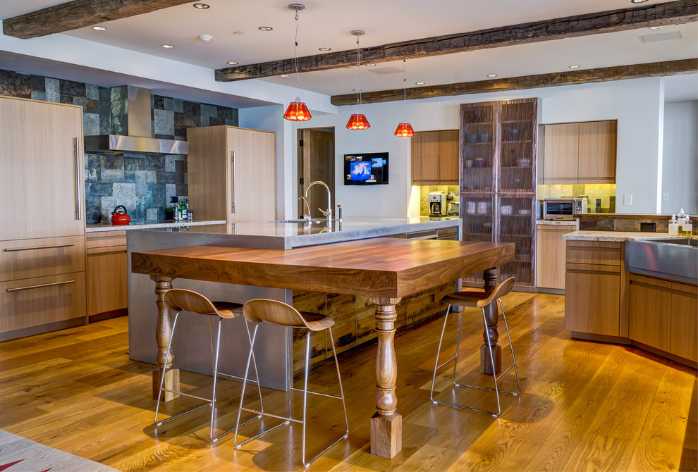 Stilmix Küche mit flächenbündigen Schrankfronten, hellen Holzschränken, Küchenrückwand in Metallic, Elektrogeräten mit Frontblende, braunem Holzboden, zwei Kücheninseln und orangem Boden in Los Angeles