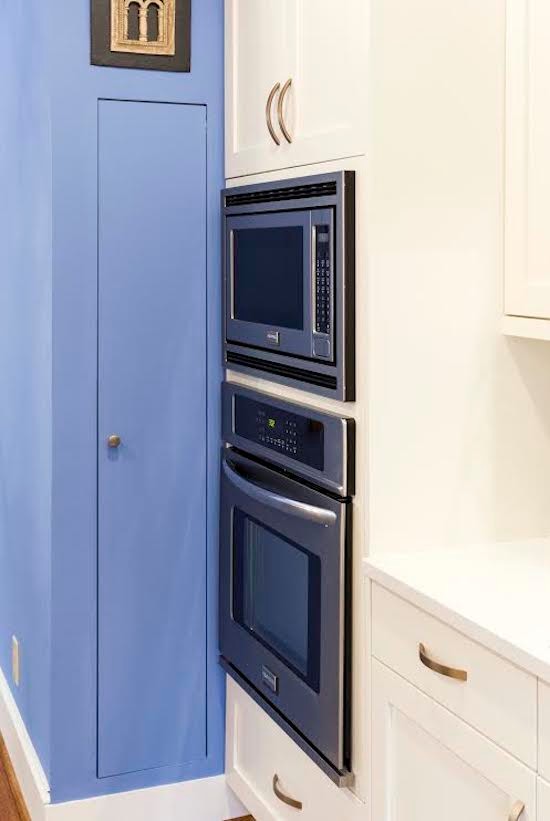 シャーロットにある中くらいな地中海スタイルのおしゃれなキッチン (アンダーカウンターシンク、シェーカースタイル扉のキャビネット、白いキャビネット、珪岩カウンター、青いキッチンパネル、シルバーの調理設備、淡色無垢フローリング) の写真