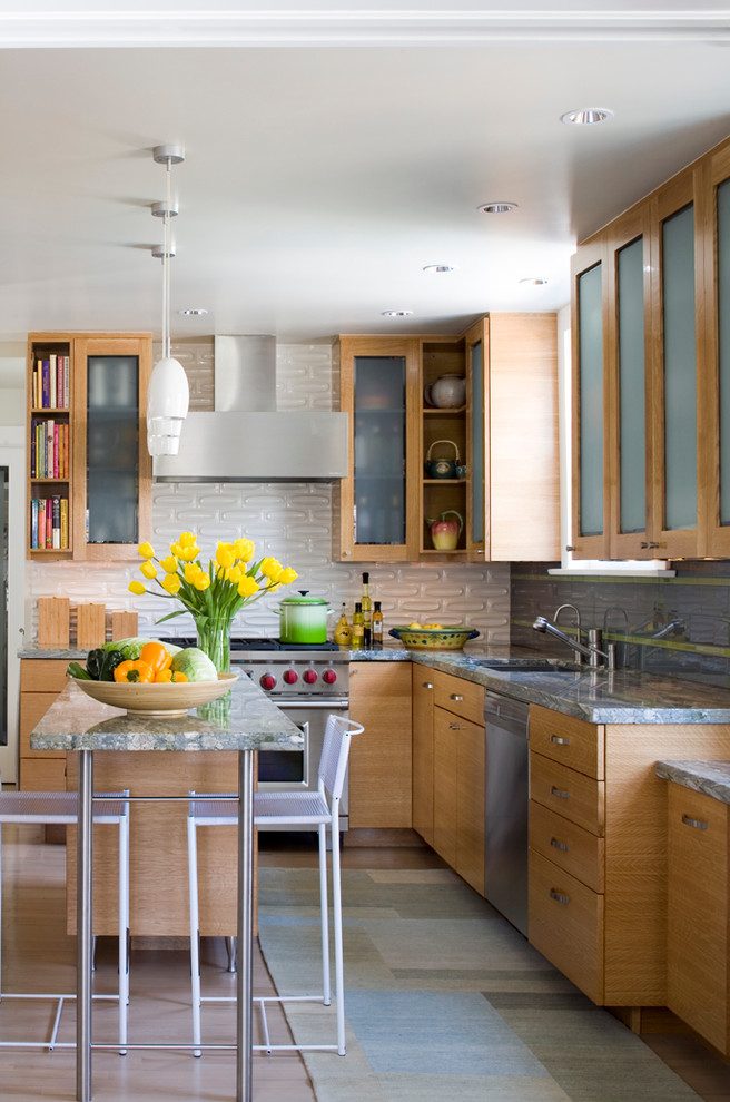 Moderne Küche in L-Form mit Glasfronten, hellbraunen Holzschränken und Kücheninsel in Denver