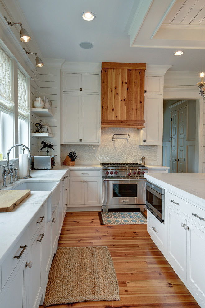 Klassische Küche in L-Form mit Landhausspüle, Schrankfronten im Shaker-Stil, weißen Schränken, Küchenrückwand in Weiß, Rückwand aus Mosaikfliesen und Elektrogeräten mit Frontblende in Charleston