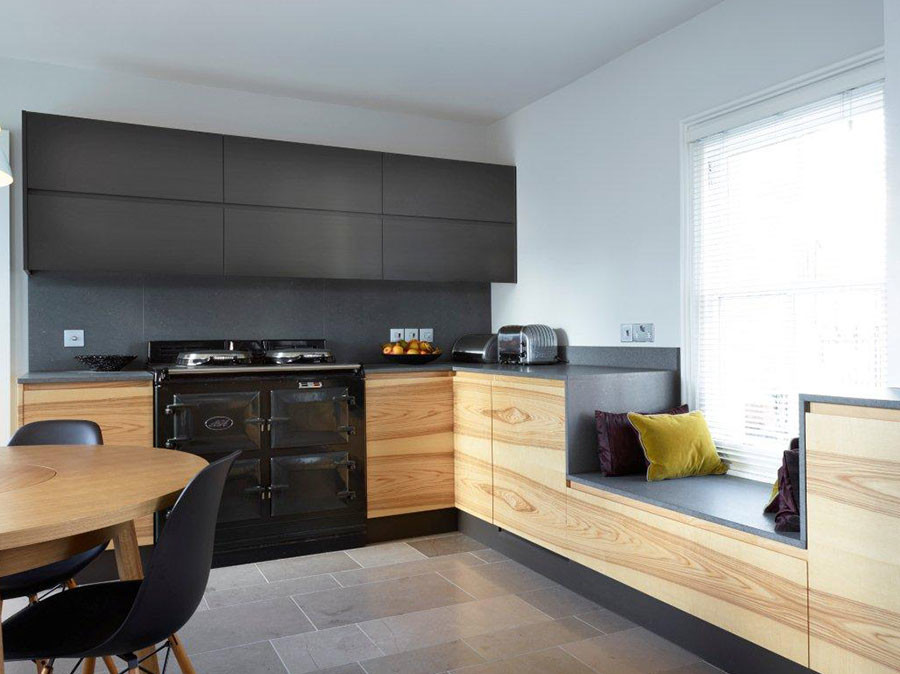 Идея дизайна: параллельная кухня в стиле модернизм с обеденным столом, врезной мойкой, плоскими фасадами, светлыми деревянными фасадами, столешницей из кварцита, серым фартуком, черной техникой и островом