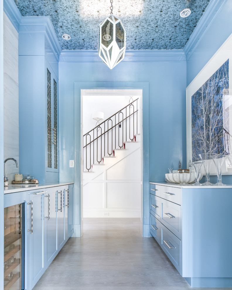 Cette image montre une arrière-cuisine parallèle traditionnelle avec un évier encastré, un placard avec porte à panneau encastré, des portes de placard bleues, une crédence blanche, aucun îlot, un sol gris et un plan de travail blanc.