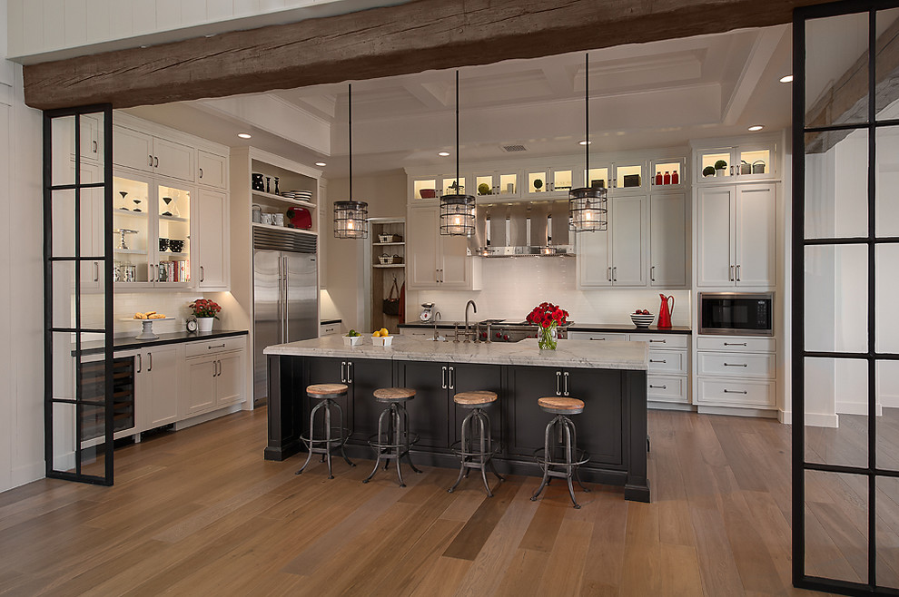 Idées déco pour une cuisine classique avec un électroménager en acier inoxydable, des portes de placard blanches, une crédence blanche et un placard à porte shaker.