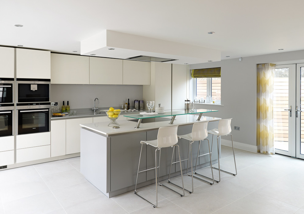 Design ideas for a contemporary kitchen in Surrey with a submerged sink, flat-panel cabinets, white cabinets, grey splashback and an island.