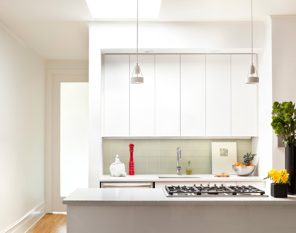 Immagine di una piccola cucina minimal con lavello sottopiano, ante lisce, ante bianche, paraspruzzi grigio, paraspruzzi con piastrelle di vetro, elettrodomestici in acciaio inossidabile e parquet chiaro