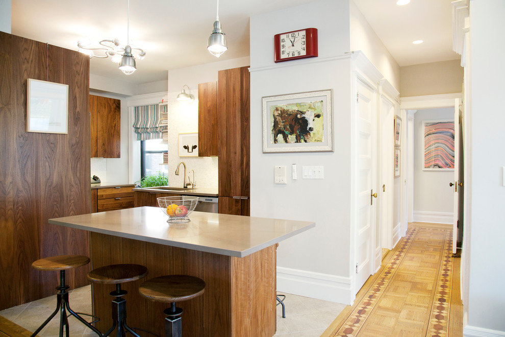 ニューヨークにある中くらいなコンテンポラリースタイルのおしゃれなキッチン (フラットパネル扉のキャビネット、シルバーの調理設備、中間色木目調キャビネット、白いキッチンパネル) の写真