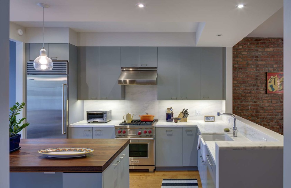 Moderne Küche in grau-weiß in L-Form mit Waschbecken, grauen Schränken, Küchenrückwand in Weiß, Küchengeräten aus Edelstahl, Kücheninsel und Rückwand aus Stein in New York