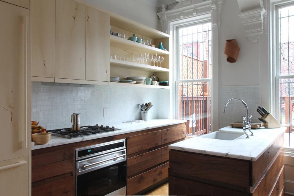 Bild på ett funkis kök, med en undermonterad diskho, släta luckor, skåp i ljust trä, vitt stänkskydd, stänkskydd i mosaik och integrerade vitvaror