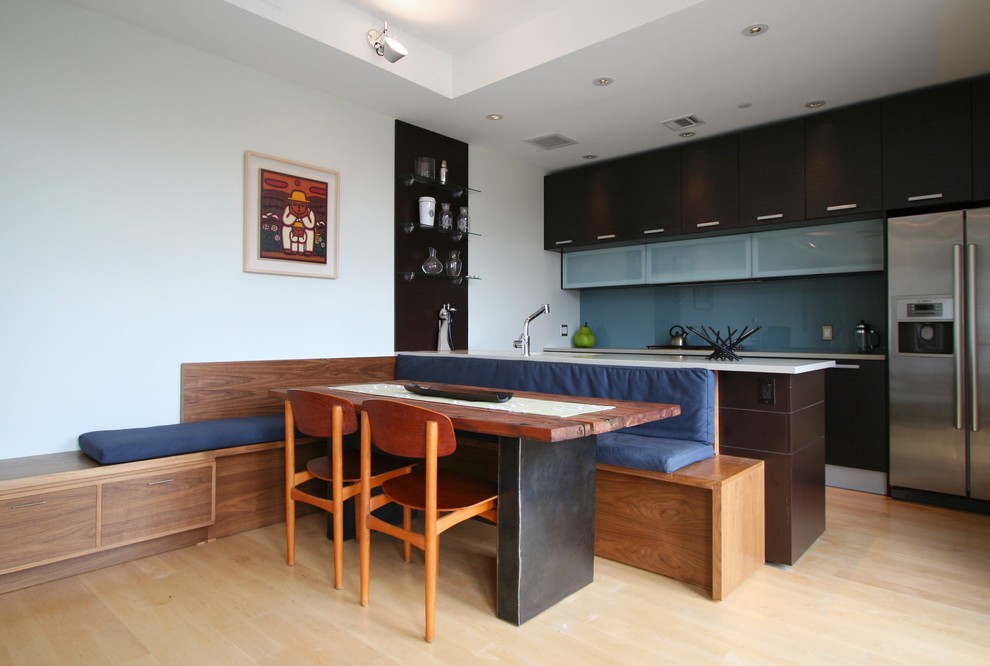 Mid-sized minimalist galley light wood floor open concept kitchen photo in New York with an undermount sink, flat-panel cabinets, dark wood cabinets, limestone countertops, blue backsplash, glass sheet backsplash, stainless steel appliances and a peninsula