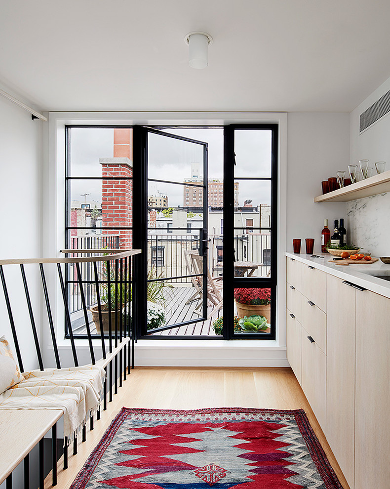 Immagine di una piccola cucina scandinava con lavello sottopiano, ante lisce, ante in legno chiaro, paraspruzzi bianco, parquet chiaro e top bianco