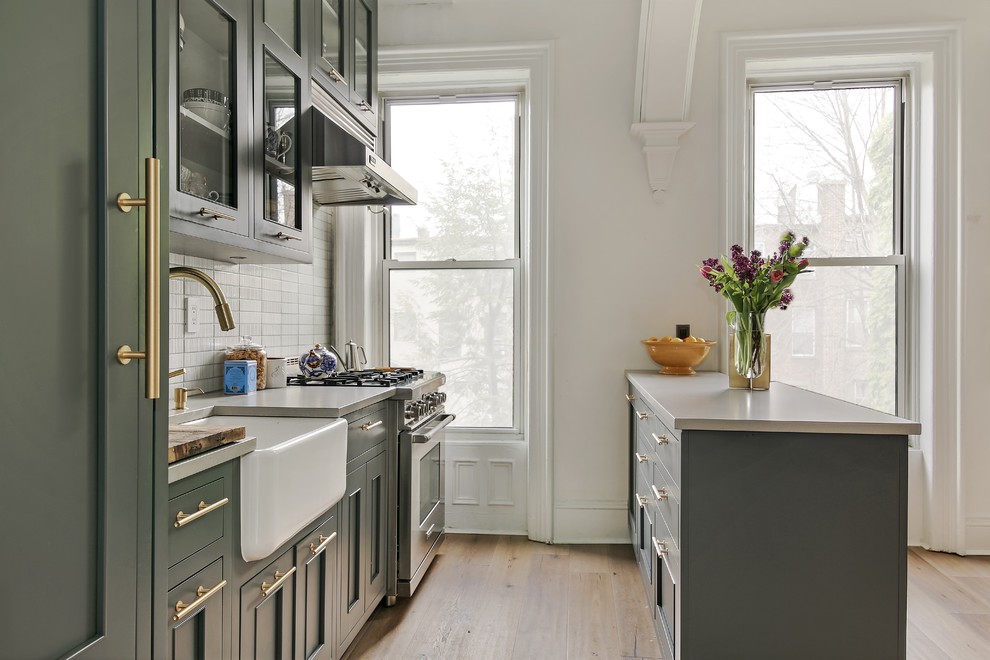 Foto på ett stort vintage linjärt kök med öppen planlösning, med en rustik diskho, skåp i shakerstil, grå skåp, bänkskiva i kvarts, vitt stänkskydd, stänkskydd i stickkakel, rostfria vitvaror, ljust trägolv, en halv köksö och beiget golv