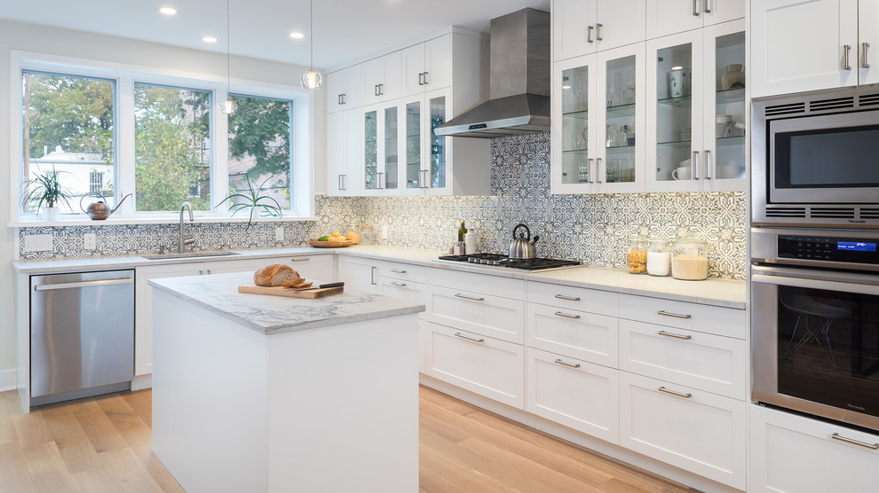 Inspiration for a mid-sized transitional l-shaped medium tone wood floor and brown floor eat-in kitchen remodel in New York with an undermount sink, shaker cabinets, white cabinets, quartzite countertops, multicolored backsplash, porcelain backsplash, stainless steel appliances and an island