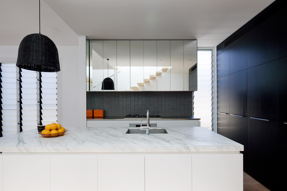 Mittelgroße Moderne Küche mit Unterbauwaschbecken, flächenbündigen Schrankfronten, weißen Schränken, Marmor-Arbeitsplatte, Küchenrückwand in Grau, Elektrogeräten mit Frontblende, hellem Holzboden und Kücheninsel in Sydney