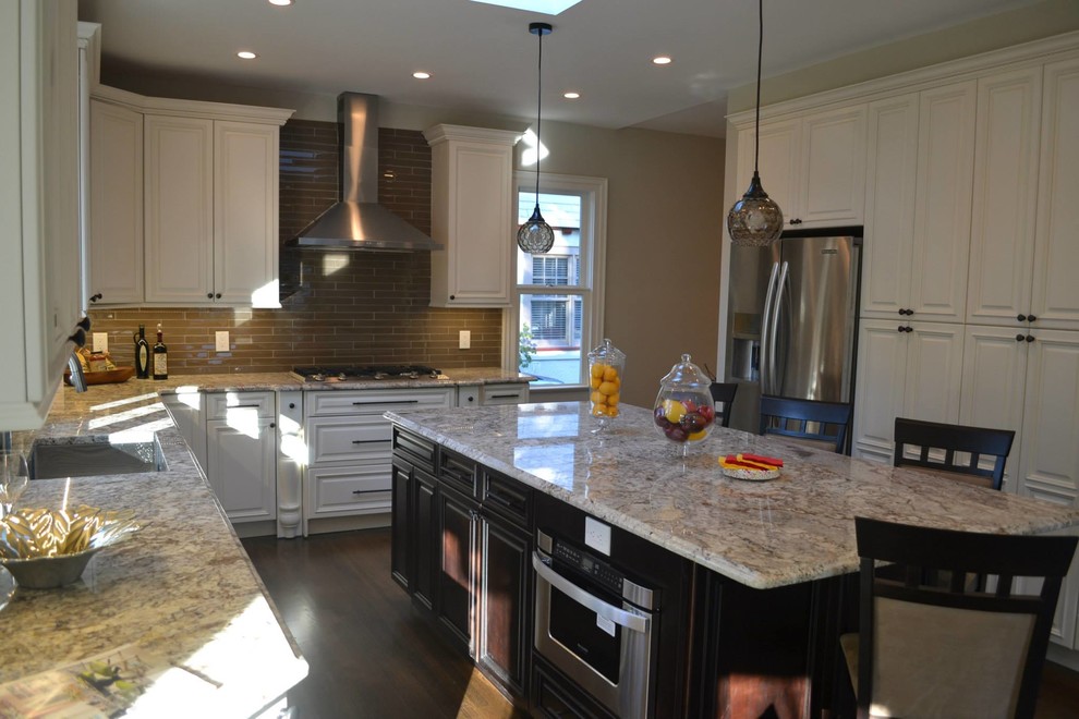Eat-in kitchen - mid-sized traditional l-shaped medium tone wood floor eat-in kitchen idea in Newark with an undermount sink, white cabinets, granite countertops, beige backsplash, subway tile backsplash, stainless steel appliances, an island and raised-panel cabinets