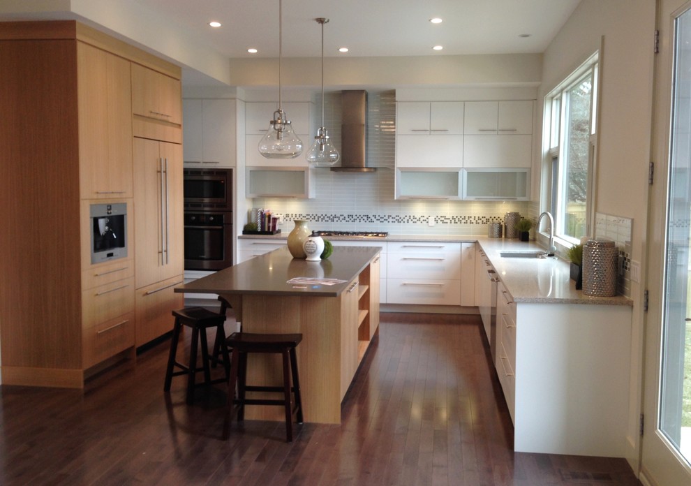 Inspiration for a mid-sized contemporary u-shaped medium tone wood floor open concept kitchen remodel in Calgary with an undermount sink, flat-panel cabinets, quartz countertops, white backsplash, glass tile backsplash, stainless steel appliances and an island