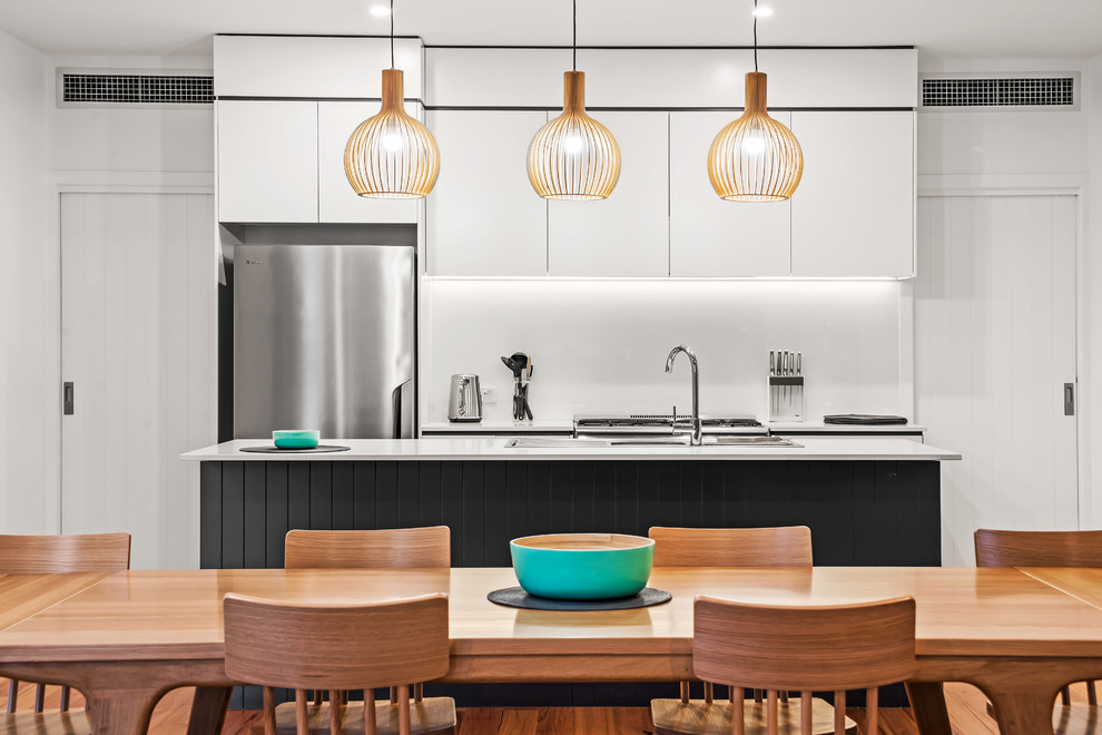 Imagen de cocina comedor contemporánea de tamaño medio con armarios con paneles lisos, salpicadero blanco, electrodomésticos de acero inoxidable, una isla, encimeras blancas y con blanco y negro