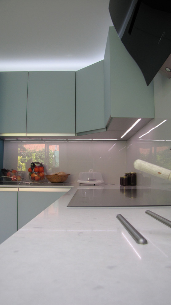 Photo of a large modern u-shaped enclosed kitchen in Other with a submerged sink, glass-front cabinets, turquoise cabinets, quartz worktops, white splashback, glass sheet splashback, stainless steel appliances, porcelain flooring, no island and beige floors.