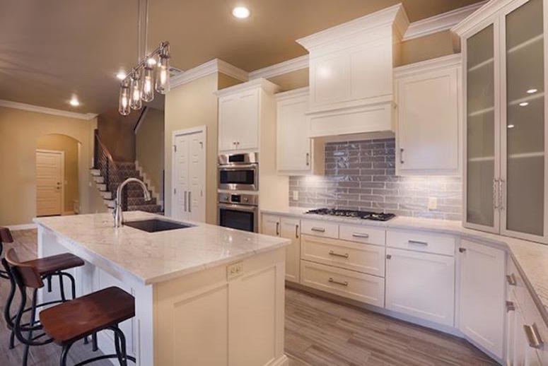 This is an example of a medium sized classic l-shaped kitchen in Oklahoma City with a submerged sink, shaker cabinets, white cabinets, grey splashback, stainless steel appliances, an island, marble worktops, glass sheet splashback and brown floors.
