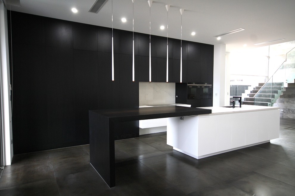 Design ideas for a large modern single-wall open plan kitchen in Sydney with a submerged sink, flat-panel cabinets, black cabinets, engineered stone countertops, white splashback, stone slab splashback, black appliances, porcelain flooring, an island and grey floors.