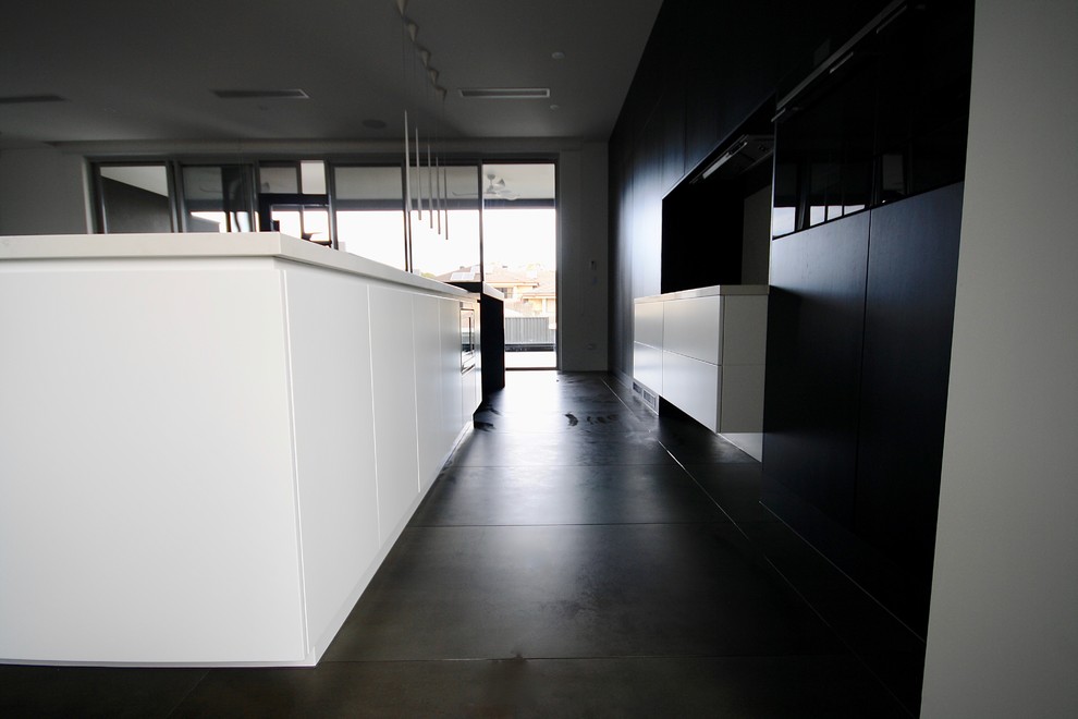 Immagine di una grande cucina moderna con lavello sottopiano, ante lisce, ante nere, top in quarzo composito, paraspruzzi bianco, paraspruzzi in lastra di pietra, elettrodomestici neri, pavimento in gres porcellanato e pavimento grigio