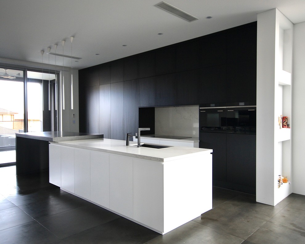 Photo of a large modern single-wall open plan kitchen in Sydney with a submerged sink, flat-panel cabinets, black cabinets, engineered stone countertops, white splashback, stone slab splashback, black appliances, porcelain flooring, an island and grey floors.