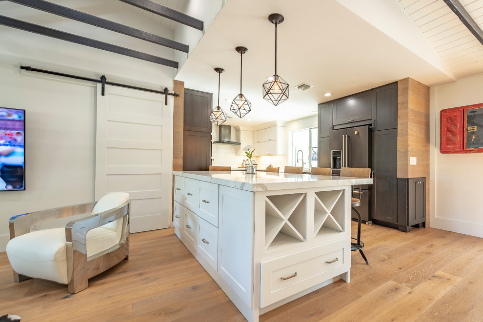 Inspiration for a farmhouse light wood floor kitchen remodel in Miami with a farmhouse sink, shaker cabinets, white cabinets, solid surface countertops, black appliances and an island