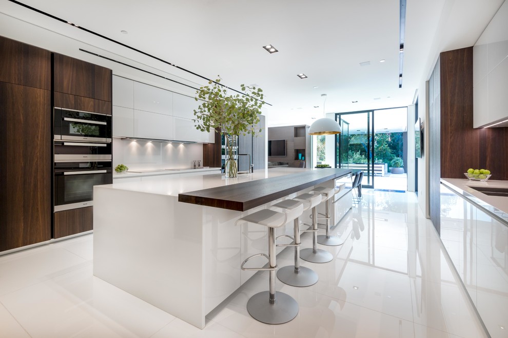 Zweizeilige, Geräumige Moderne Wohnküche mit flächenbündigen Schrankfronten, weißen Schränken, Küchengeräten aus Edelstahl, Porzellan-Bodenfliesen und Kücheninsel in Los Angeles