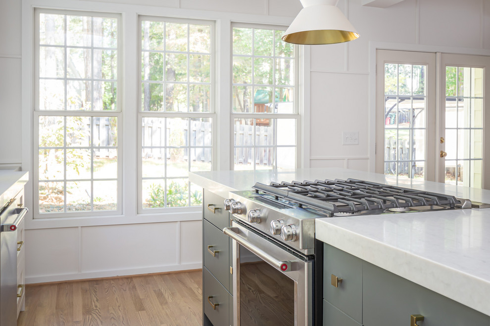 ローリーにある高級な中くらいなカントリー風のおしゃれなキッチン (エプロンフロントシンク、フラットパネル扉のキャビネット、白いキャビネット、珪岩カウンター、白いキッチンパネル、サブウェイタイルのキッチンパネル、パネルと同色の調理設備、淡色無垢フローリング、白いキッチンカウンター) の写真