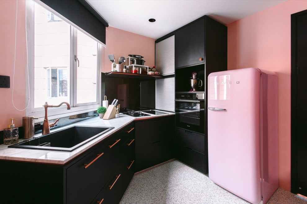 Diseño de cocinas en L actual con fregadero encastrado, armarios con paneles lisos, puertas de armario negras, electrodomésticos de colores y encimeras blancas