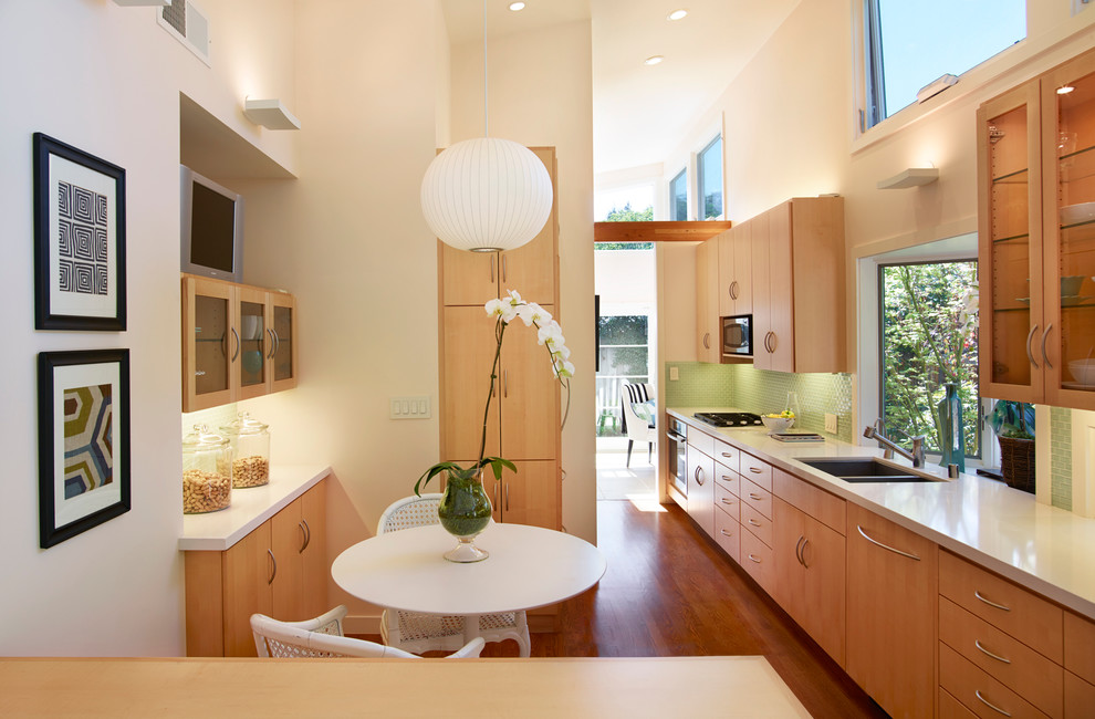 Enclosed kitchen - transitional single-wall medium tone wood floor enclosed kitchen idea in San Francisco with a double-bowl sink, flat-panel cabinets, medium tone wood cabinets and green backsplash
