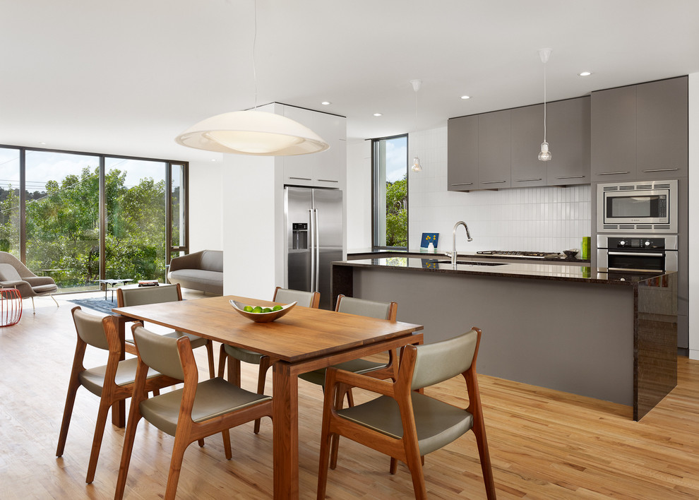 Immagine di una cucina abitabile minimalista con ante lisce, ante grigie e elettrodomestici in acciaio inossidabile