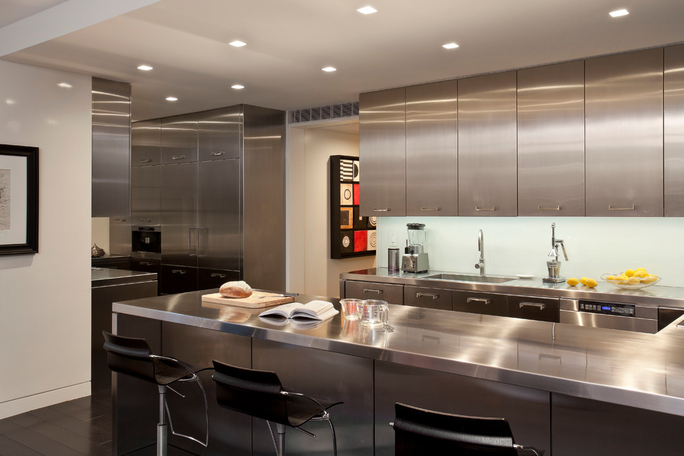 Kitchen - contemporary u-shaped dark wood floor kitchen idea in New York with an integrated sink, flat-panel cabinets, stainless steel cabinets, stainless steel countertops, glass sheet backsplash, stainless steel appliances, a peninsula and blue backsplash