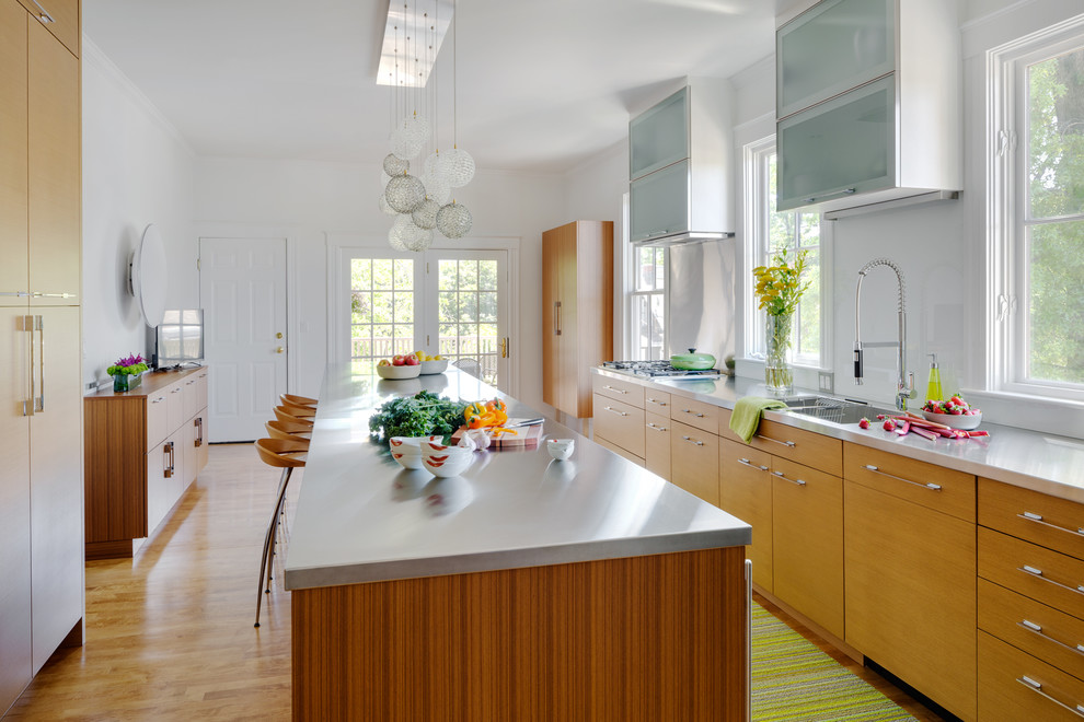Inspiration for a small contemporary medium tone wood floor enclosed kitchen remodel in Boston with an integrated sink, flat-panel cabinets, medium tone wood cabinets, stainless steel countertops, white backsplash, stainless steel appliances and an island