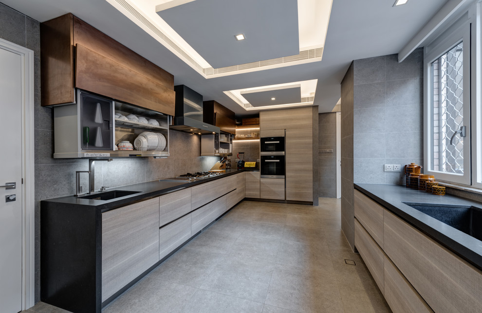 Contemporary u-shaped kitchen in Hong Kong with a submerged sink, flat-panel cabinets, grey cabinets, grey splashback, black appliances, no island, grey floors and black worktops.