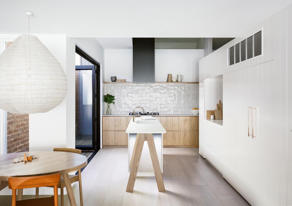 Diseño de cocina actual con armarios con paneles lisos, puertas de armario blancas, suelo de madera clara, una isla y suelo beige