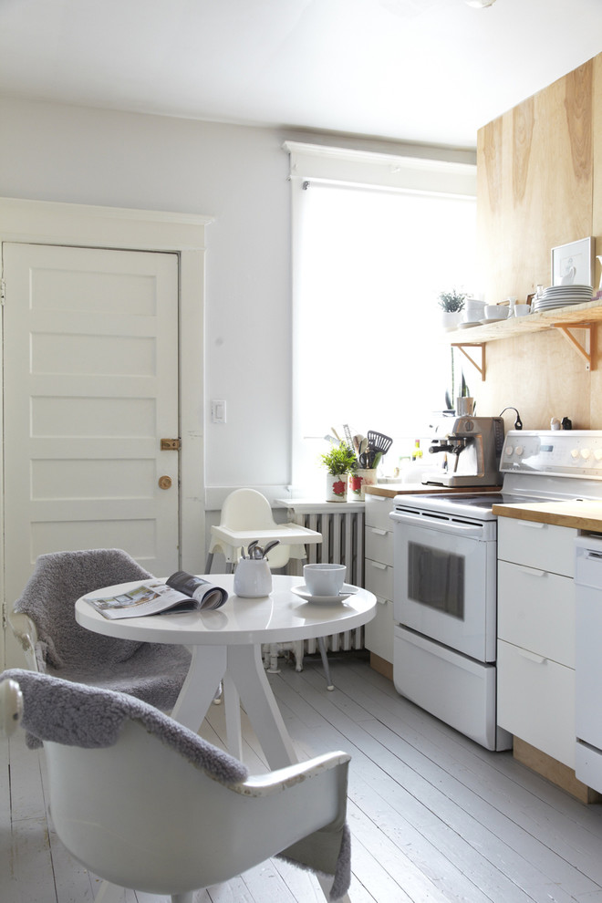 Einzeilige Nordische Wohnküche mit flächenbündigen Schrankfronten, weißen Schränken, Arbeitsplatte aus Holz, weißen Elektrogeräten, gebeiztem Holzboden und weißem Boden in Toronto