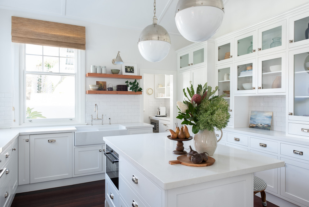 Immagine di una cucina tradizionale di medie dimensioni con lavello stile country, ante in stile shaker, ante bianche, paraspruzzi bianco, pavimento marrone e top bianco