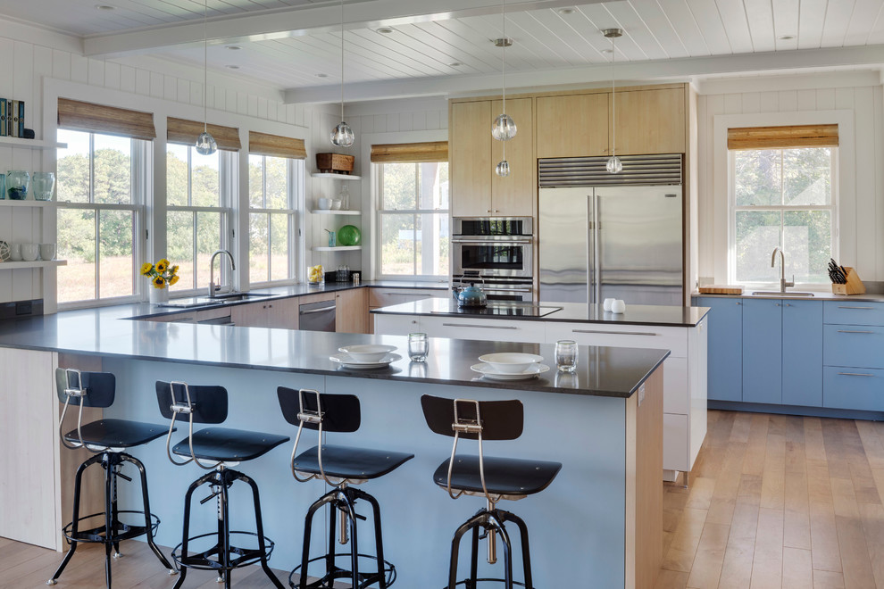 This is an example of a large retro u-shaped kitchen/diner in Boston with a submerged sink, flat-panel cabinets, stainless steel appliances, light hardwood flooring, blue cabinets, an island and brown floors.