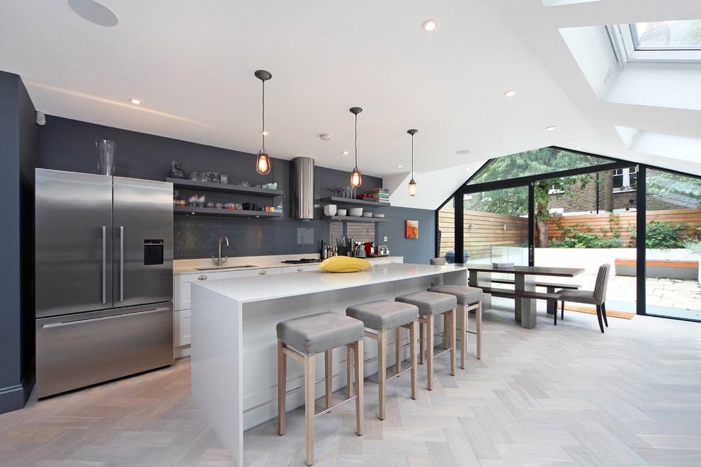 Große Moderne Wohnküche mit Unterbauwaschbecken, Granit-Arbeitsplatte, Küchenrückwand in Grau, Küchengeräten aus Edelstahl, hellem Holzboden, Kücheninsel, offenen Schränken, grauen Schränken und Glasrückwand in London