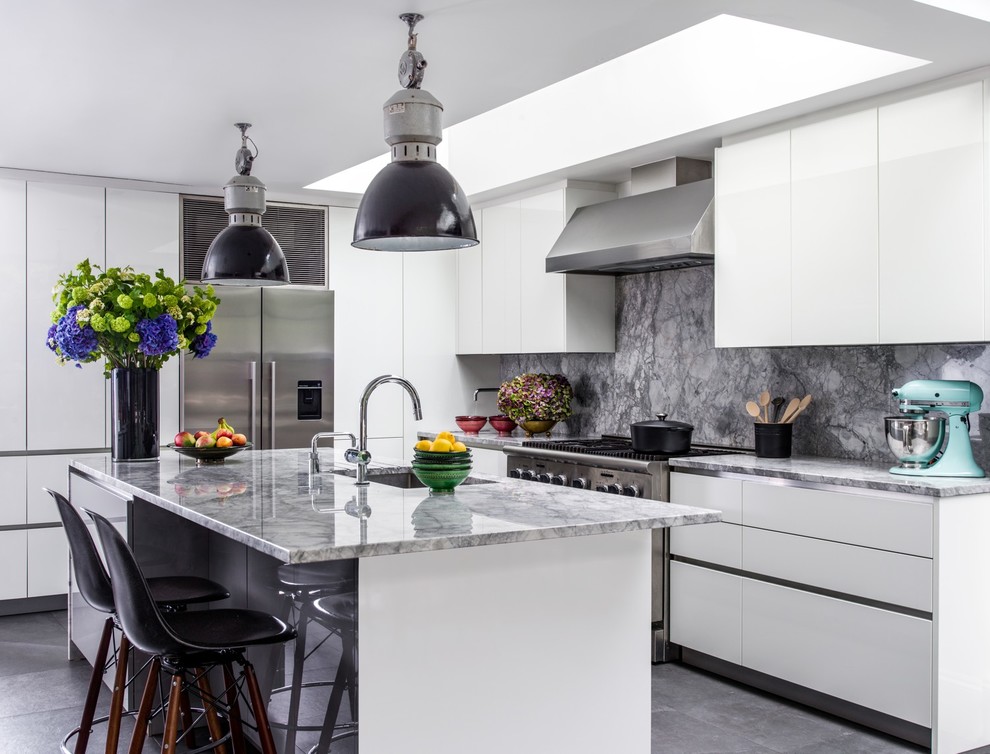 Inredning av ett modernt stort grå grått l-kök, med en undermonterad diskho, släta luckor, vita skåp, grått stänkskydd, rostfria vitvaror, en köksö, grått golv och marmorbänkskiva