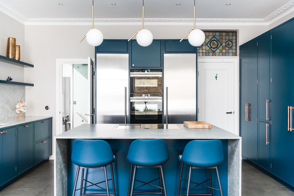 Moderne Küche mit flächenbündigen Schrankfronten, blauen Schränken, Küchenrückwand in Grau, Küchengeräten aus Edelstahl, Kücheninsel, grauem Boden und grauer Arbeitsplatte in London