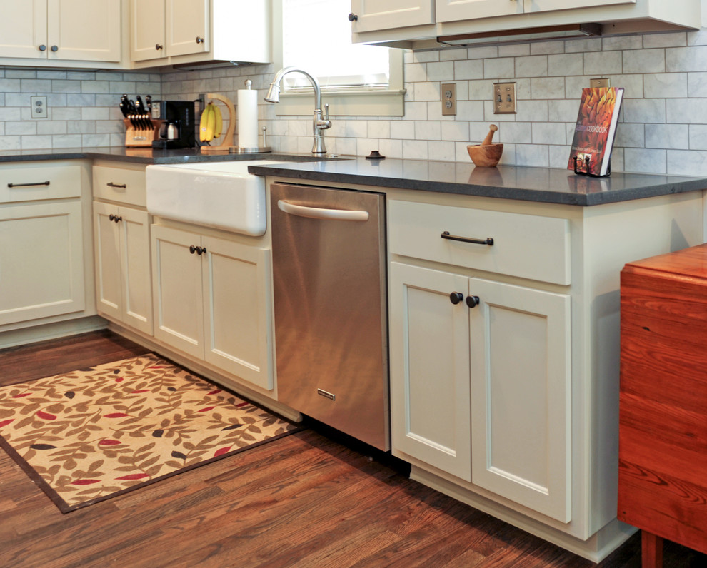Inspiration for a mid-sized transitional l-shaped medium tone wood floor enclosed kitchen remodel in Atlanta with a farmhouse sink, shaker cabinets, white cabinets, soapstone countertops, multicolored backsplash, subway tile backsplash, stainless steel appliances and no island