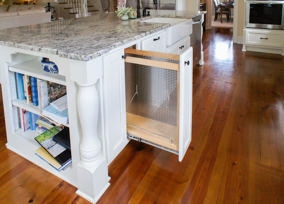 Foto de cocina de estilo americano grande con armarios estilo shaker, puertas de armario blancas, fregadero bajoencimera, encimera de granito, salpicadero beige, salpicadero de azulejos tipo metro, electrodomésticos de acero inoxidable, suelo de madera en tonos medios y una isla