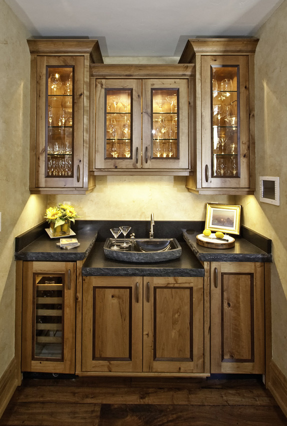 Example of a mountain style single-wall enclosed kitchen design in Denver with raised-panel cabinets, distressed cabinets, soapstone countertops, gray backsplash, stone slab backsplash and paneled appliances