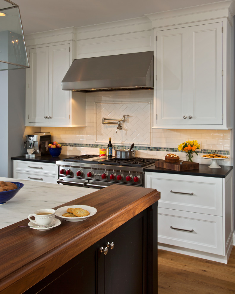 ボストンにある広いトラディショナルスタイルのおしゃれなキッチン (白いキャビネット、白いキッチンパネル、磁器タイルのキッチンパネル、シルバーの調理設備、無垢フローリング、落し込みパネル扉のキャビネット) の写真