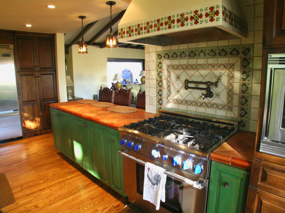 Exempel på ett stort medelhavsstil kök, med en halv köksö, luckor med upphöjd panel, skåp i mörkt trä, kaklad bänkskiva, vitt stänkskydd, stänkskydd i keramik, rostfria vitvaror, en nedsänkt diskho och mellanmörkt trägolv