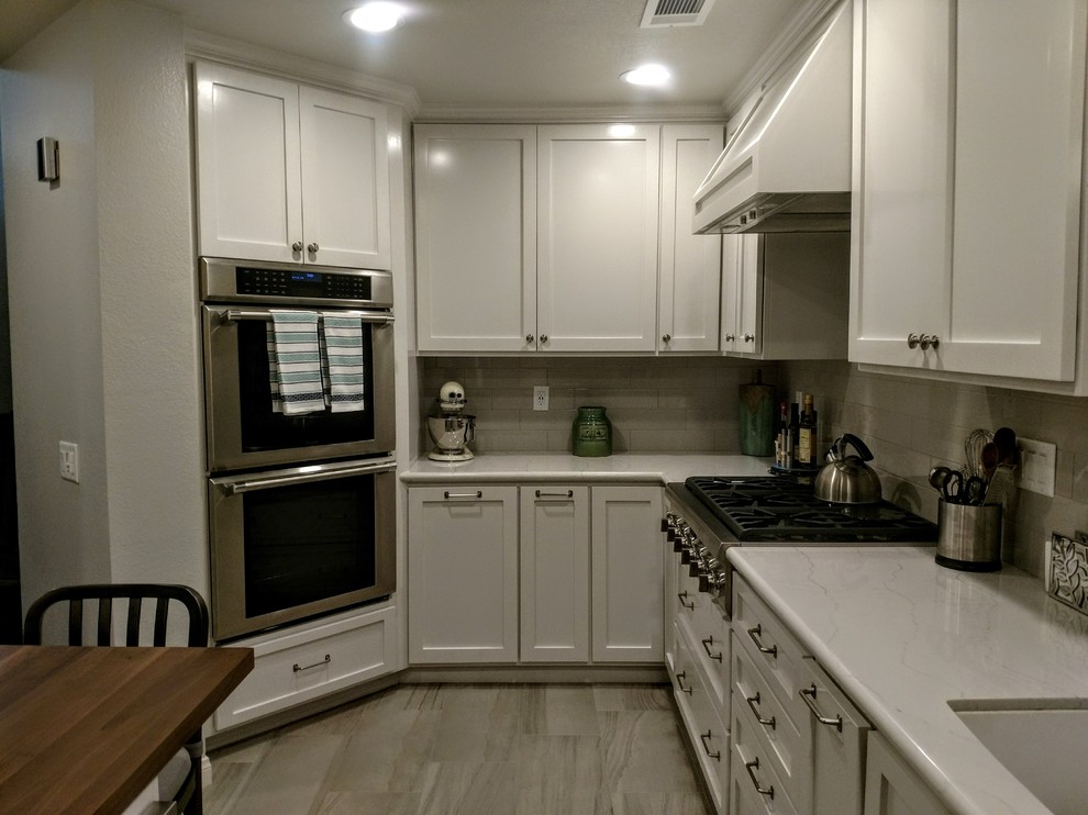 Photo of a classic kitchen in Orange County with a submerged sink, shaker cabinets, white cabinets, engineered stone countertops, grey splashback, metro tiled splashback, stainless steel appliances, porcelain flooring and grey floors.
