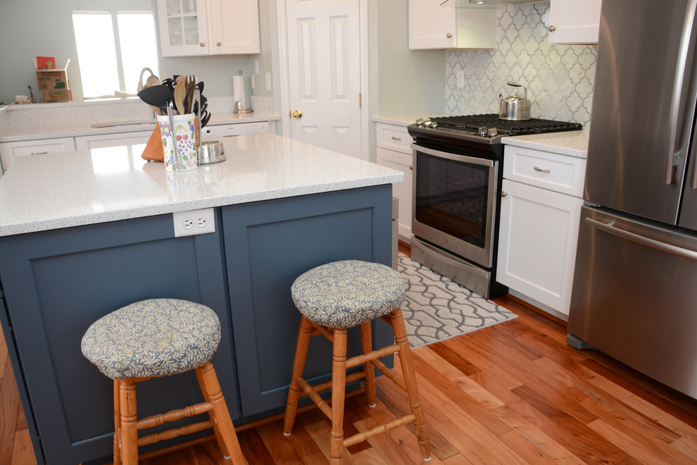 Eat-in kitchen - mid-sized transitional l-shaped medium tone wood floor and brown floor eat-in kitchen idea in Baltimore with a single-bowl sink, recessed-panel cabinets, white cabinets, quartz countertops, white backsplash, stainless steel appliances and an island